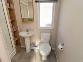 A bathroom with a toilet sink mirror wooden shelf and a window at HD Retreat in Tattershall