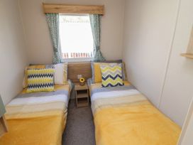 A bedroom with two single beds and a small wooden nightstand with a flower at HD Retreat in Tattershall