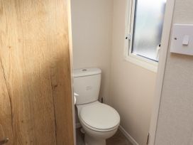 A small bathroom with a white toilet next to a frosted window at HD Retreat in Tattershall
