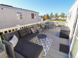An outdoor deck with cushioned wicker sofa table and chairs at HD Retreat in Tattershall