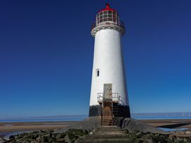 A lighthouse with stairs and a metal door on a rocky beach under a clear blue sky at Rivendell in Ffynnongroyw