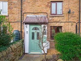 A green front door with glass panels on a stone house with a small tree and bushes at Rivendell in Ffynnongroyw