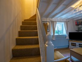 A carpeted staircase next to a living room with a window a television and a wooden chair at Rivendell in Ffynnongroyw