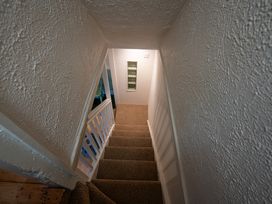 A narrow staircase with carpeted steps and white textured walls at Rivendell in Ffynnongroyw