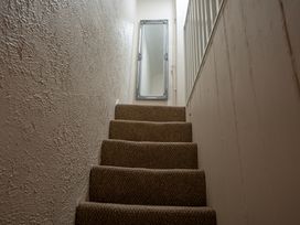 A carpeted staircase with textured walls and a rectangular mirror at the top at Rivendell in Ffynnongroyw