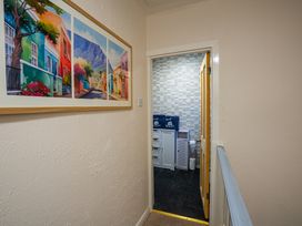 A hallway with a framed painting on the wall leading to a bathroom with cabinets and towels at Rivendell in Ffynnongroyw
