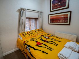 A bedroom with a bed with yellow patterned bedding towels on the bed next to it and two framed pictures on the wall at Rivendell in Ffynnongroyw