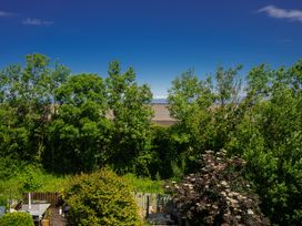 A garden with trees and shrubs overlooking a body of water at Rivendell in Ffynnongroyw