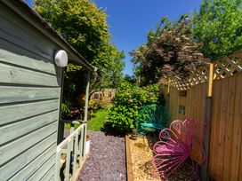 A garden area with a wooden shed a gravel path metal garden chairs and green plants at Rivendell in Ffynnongroyw