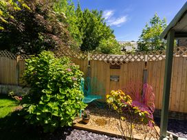 A garden area with pink and blue metal chairs surrounded by plants and a wooden fence at Rivendell in Ffynnongroyw