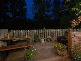 A wooden outdoor patio with a picnic table bench and plants in pots at Rivendell in Ffynnongroyw