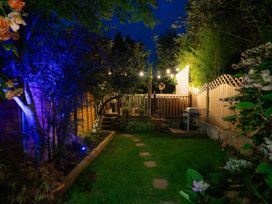 A garden area with grass stepping stones string lights and a barbecue at Rivendell in Ffynnongroyw