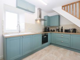 A kitchen with cabinets, sink and appliances at Trefor Ganol Beaumaris
