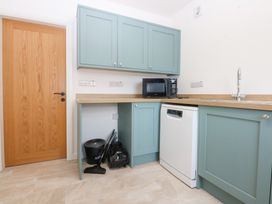 A kitchen with cabinets, a microwave, and a dishwasher at Trefor Ganol Beaumaris
