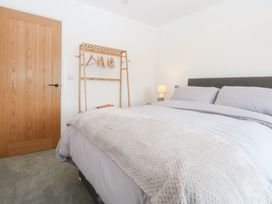 A bedroom with a bed and a clothes rail at Trefor Ganol in Beaumaris