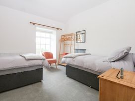 A bedroom with two beds and a chair at Trefor Ganol in Beaumaris