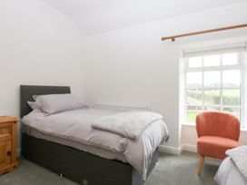A bedroom with two beds and a chair at Trefor Ganol Beaumaris