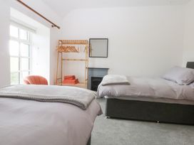 A bedroom with two beds and a clothes rack at Trefor Ganol Beaumaris