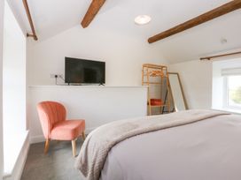 A bedroom with a bed a chair and a television at Trefor Ganol in Beaumaris