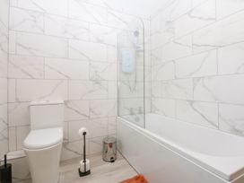 A bathroom with a bathtub and toilet at Trefor Ganol Beaumaris