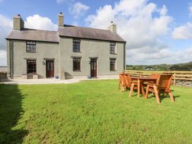 A house with a dining table and chairs in the garden at Trefor Ganol Beaumaris