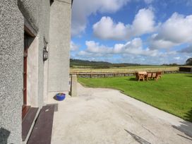 A table and chairs on grass with a door at Trefor Ganol Beaumaris