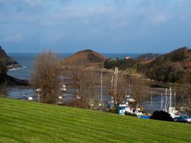A view of boats in the water with hills and trees at Watermouth Castle, West Tower Apartment Ilfracombe