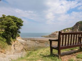 A view of the ocean from a bench surrounded by trees at Watermouth Castle, West Tower Apartment in Ilfracombe