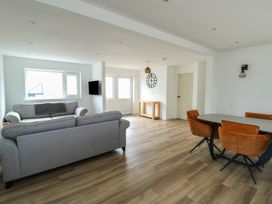 A living room with a sofa and dining area at 6 Gwelfor Estate