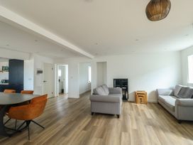 A living room with a sofa, armchairs, and a dining table at 6 Gwelfor Estate