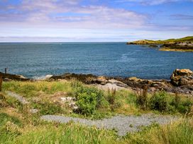 A coastal view with rocks and grass at 6 Gwelfor Estate in Cemaes Bay