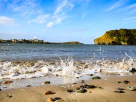 A beach with waves and rocks at 6 Gwelfor Estate Cemaes Bay