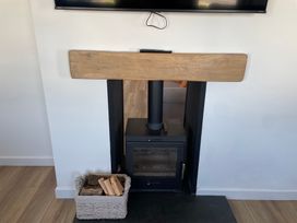 A wood stove with a wooden mantel and television at 6 Gwelfor Estate Cemaes Bay