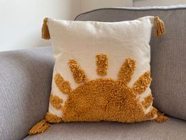 A cushion with a sun design on a couch at 6 Gwelfor Estate in Cemaes Bay