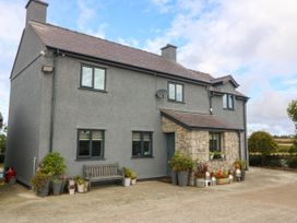 A house with a bench and planters at Tyn Rallt in Newborough