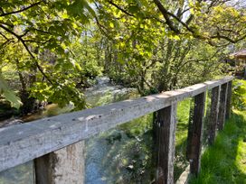 An outdoor area with a wooden railing overlooking a stream at Glas y Dorlan, Nevern near Newport, Pembrokeshire