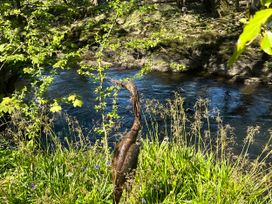 A heron sculpture near a river with grass and flowers at Glas y Dorlan near Newport, Pembrokeshire