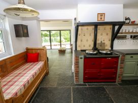 A kitchen with a wooden sofa and red stove at Glas y Dorlan Nevern near Newport, Pembrokeshire