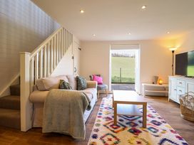 A living room with a sofa near stairs a coffee table and a television at The Stables in Tafarn-Y-Gelyn