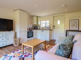 A small open plan living room and kitchen with a sofa coffee table and television at The Stables in Tafarn-Y-Gelyn