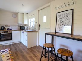 A kitchen with wooden stools a high table a door and kitchen cabinets at The Stables in Tafarn-Y-Gelyn