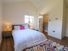 A bedroom with a bed lamps on bedside tables and a patterned rug at The Stables in Tafarn-Y-Gelyn