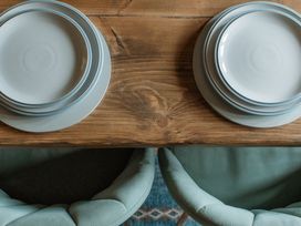 A dining table with stacked plates and chairs at Grey Walls in Glenridding
