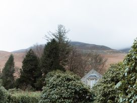 A view of a house and trees with mountains in the background at Grey Walls in Glenridding