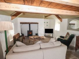 A living room with a wood stove a beige sofa green armchair and a wooden coffee table at Bryn Canaid in Uwchmynydd near Aberdaron