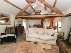 A living room with a beige sofa a green armchair wooden beams and a wooden coffee table at Bryn Canaid in Uwchmynydd near Aberdaron