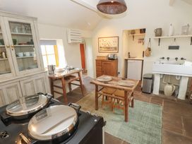 A kitchen with a wooden table and chairs a sink a cabinet and a stove at Bryn Canaid in Uwchmynydd near Aberdaron
