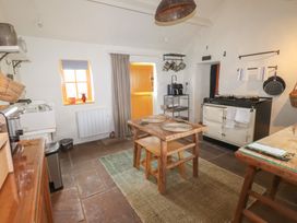 A kitchen with a wooden table and chairs a stove and kitchen utensils at Bryn Canaid in Uwchmynydd near Aberdaron