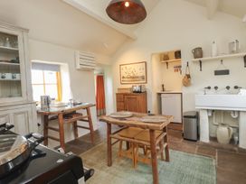 A kitchen with a wooden dining table and chairs a sink refrigerator and wooden cabinet at Bryn Canaid in Uwchmynydd near Aberdaron