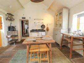 A kitchen with a wooden table and stools a stove and a cabinet at Bryn Canaid in Uwchmynydd near Aberdaron